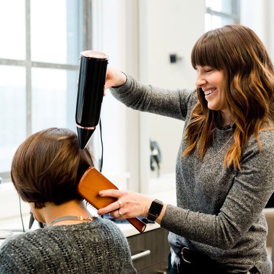 Woman blowdrying hair in salon