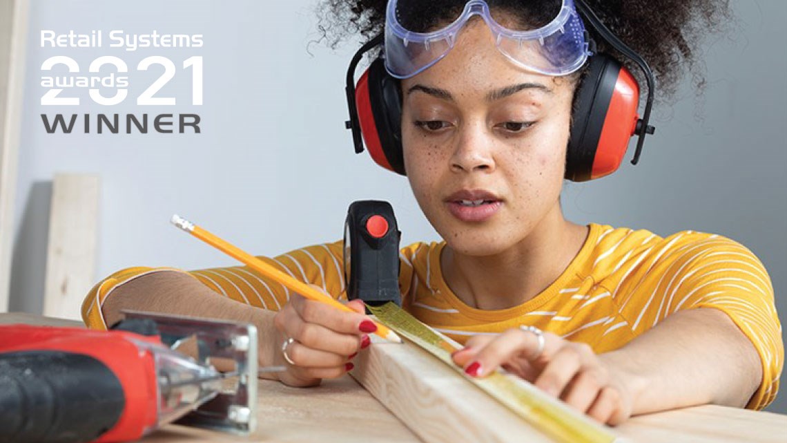 Woman measuring piece of wood and Retail Systems 2021 award winner logo