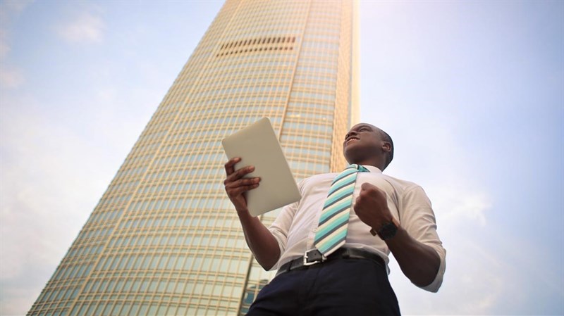 Man with tablet in front of skyscraper