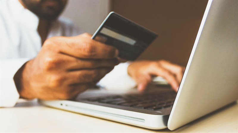 man using payment card with laptop