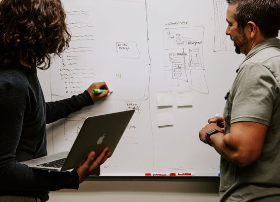 Two ecommerce consultants noting down ideas on a white board