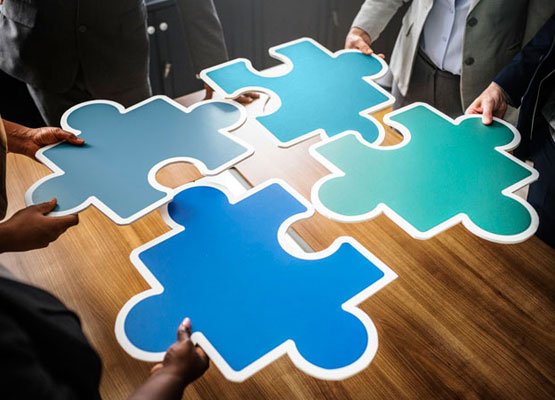 people holding pieces of a big jigsaw puzzle