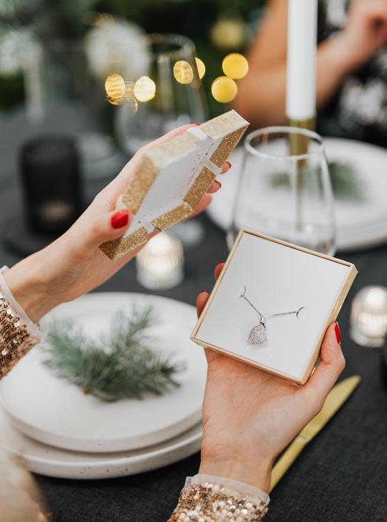 woman opening box with necklace inside